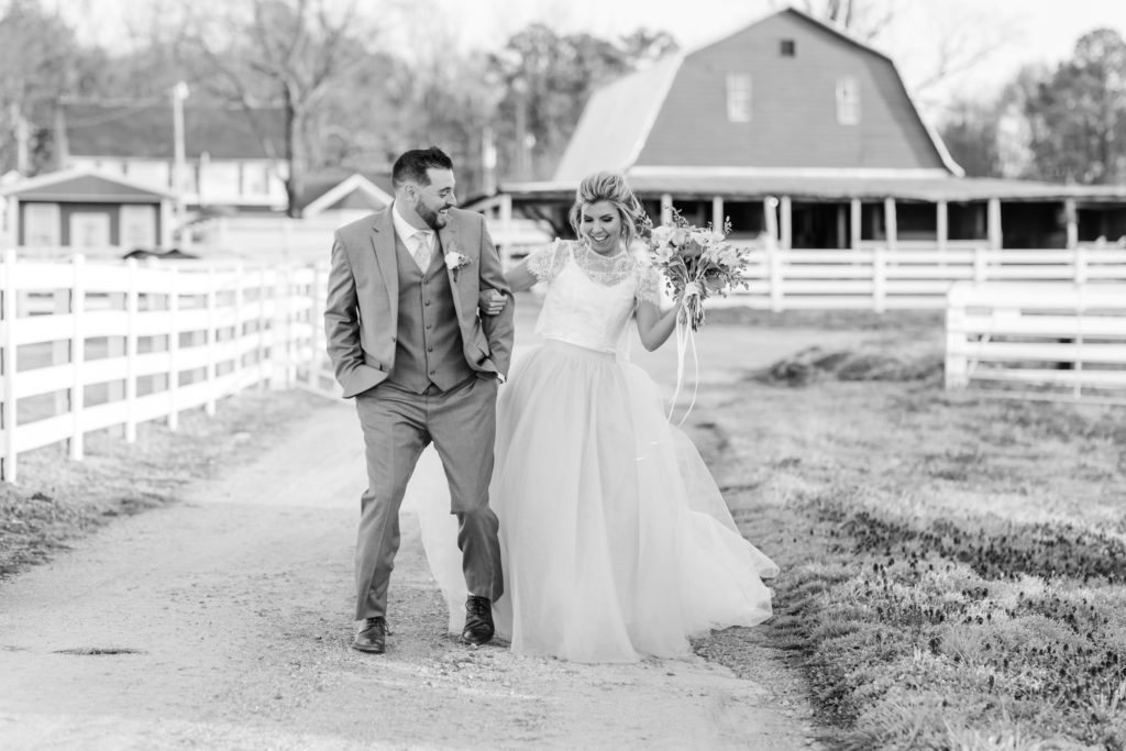 A couple beside the barn and white farm fences